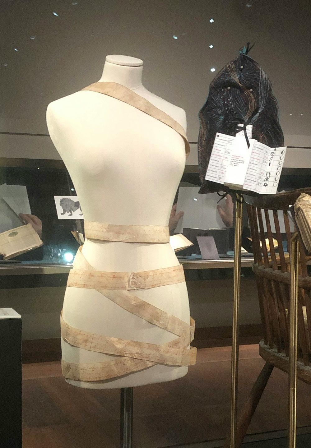 A dressmaker's dummy with a long thin 'ribbon' of material wrapped around the hips, wait and neck replicating the use of a medieval birth scroll.