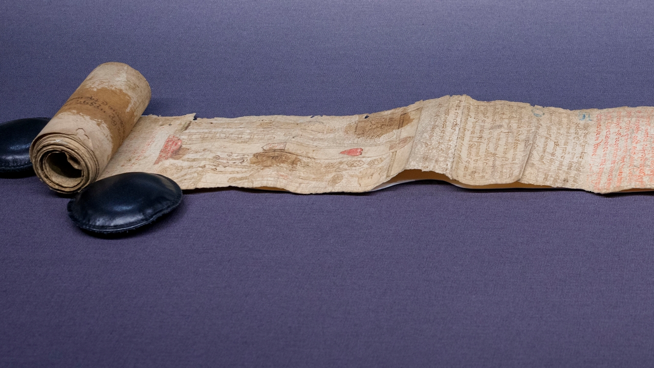 A partially unrolled parchment scroll with faded text, images and stains on its surface, from c1500 CE. Featured in an exhibition at Wellcome Collection: 'Expecting: Birth, Belief and Protection', 24 October 2025 – 19 April 2026.