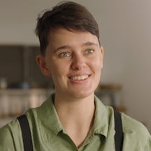 Head and shoulders photo of a young person with short dark hair. They are smiling and facing the viewer but looking to the right of the image.