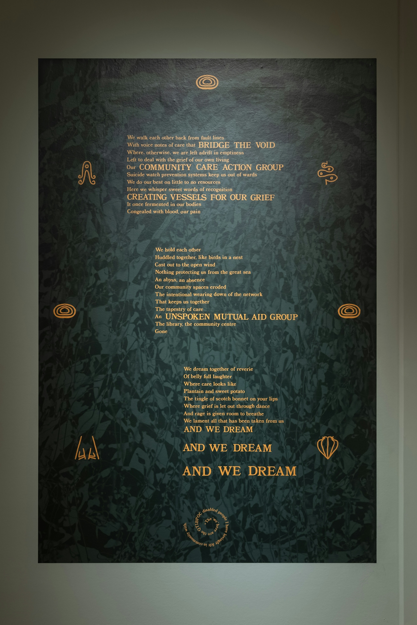 Photograph of a text-based artwork with poetry in gold lettering on a dark green background.