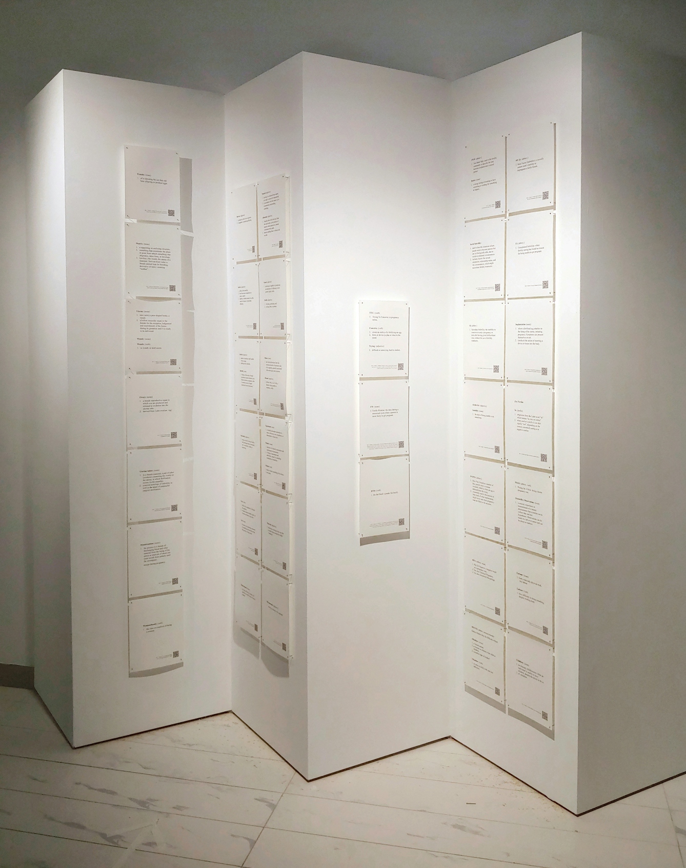 A concertina screen with pages of text pinned to all of the panels. Part of 'A Glossary With(in)Fertile Terms', an artwork by Sally Butcher.