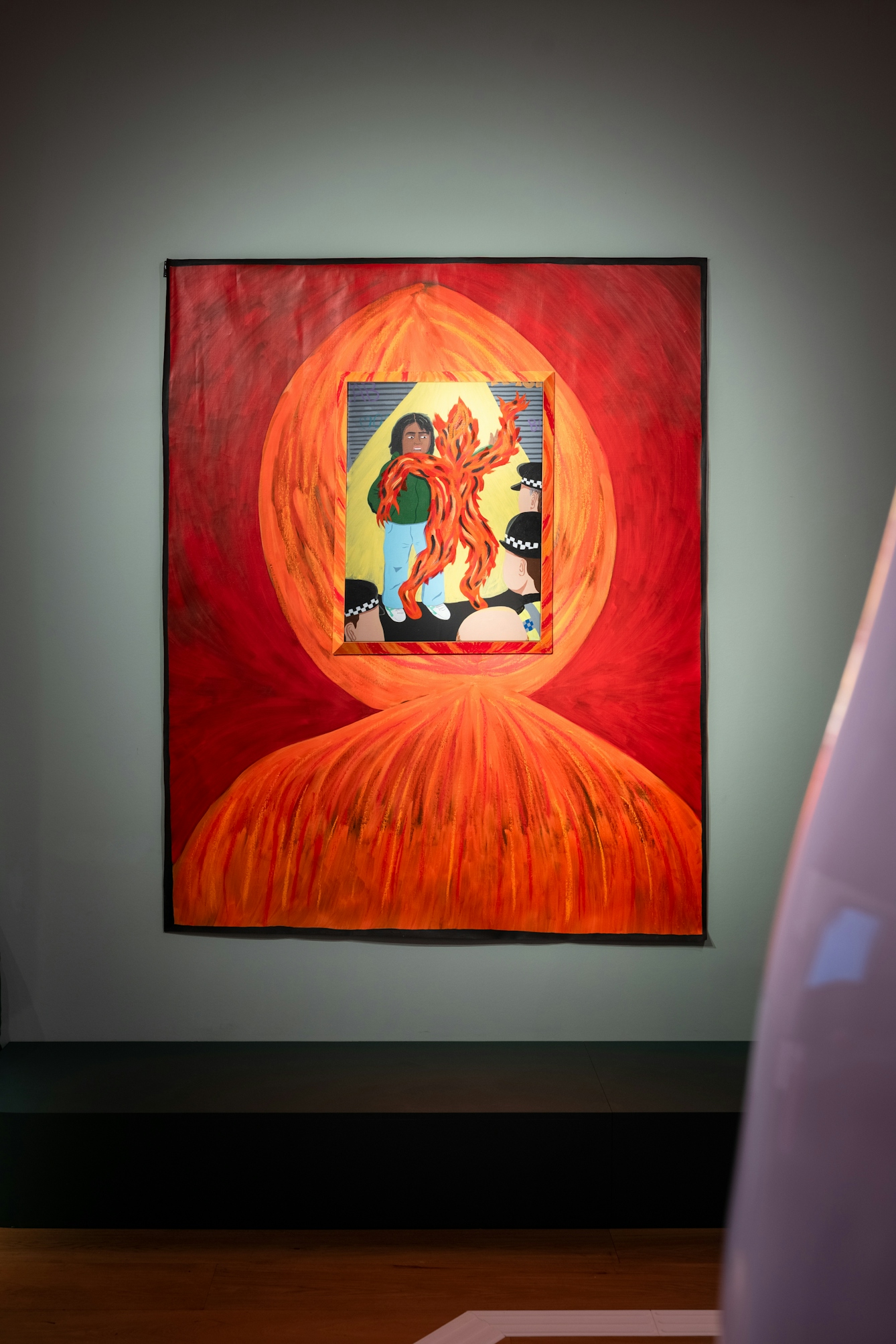 Photograph of a large orange and red painting featuring a smaller image of a figure surrounded by flame-like forms.